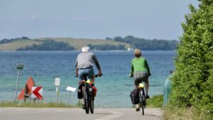two peropl riding their bikes near the sea