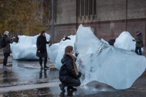 Woman kneeling touching a large block of ice